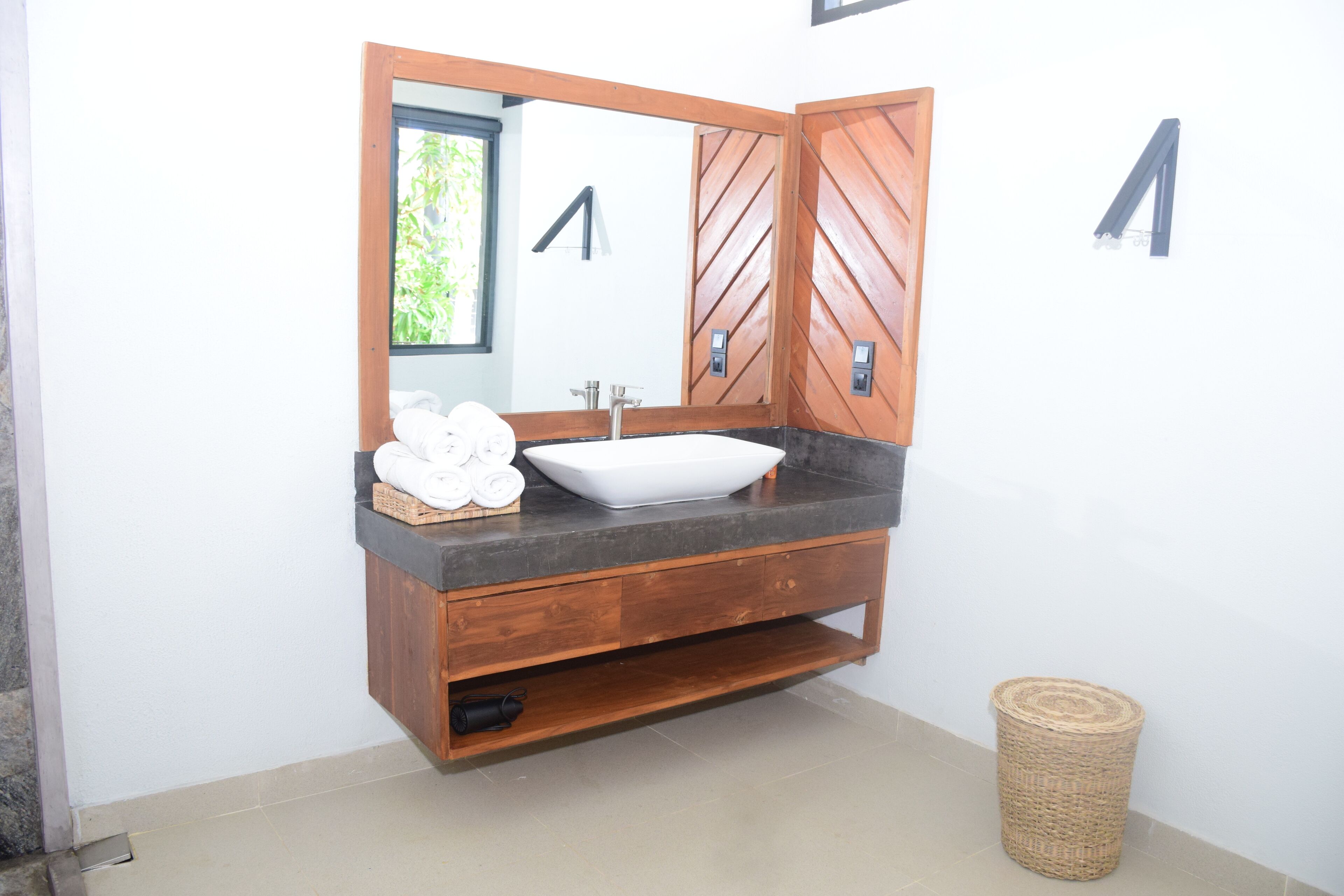 A bathroom with a wooden vanity, a white sink, and a large mirror.