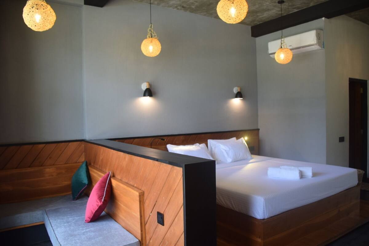 A hotel room with a wooden headboard, a large bed with white linens, and two wall-mounted light fixtures.