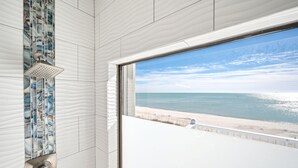 Un baño con ducha, vistas a la playa y un ventanal.