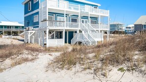 Un edificio frente al mar con varios pisos, balcones y una escalera que conduce a los niveles superiores.