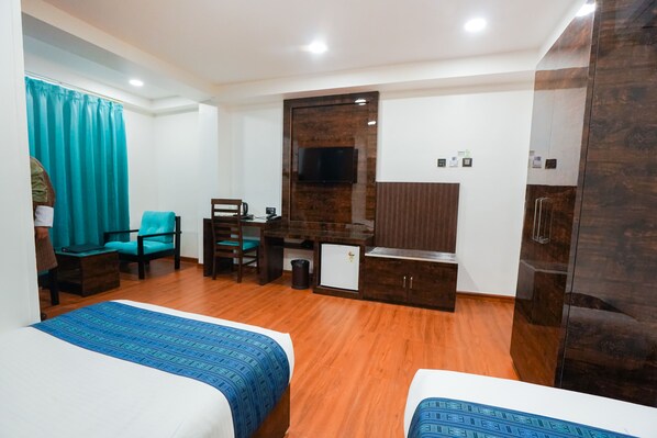 Habitación de hotel con dos camas, un escritorio con silla, televisión y armario.