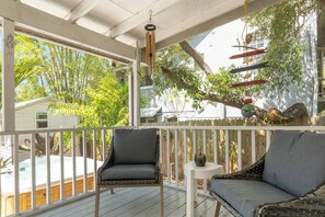 Eine überdachte Veranda mit Korbstühlen, einem kleinen Tisch und hängenden Dekorationen.