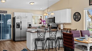 A modern kitchen with white cabinets, stainless steel appliances, and a central island with bar stools. - Private home near Zion & state parks, BBQ, cozy stay for family & friends in scenic red rock views! (La Verkin)