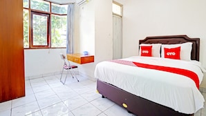 Un dormitorio ordenado con cama, escritorio y silla.