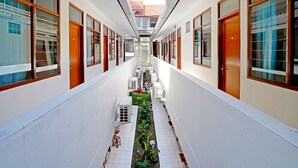 Un estrecho pasillo con paredes blancas y puertas de madera que conduce a una escalera central.