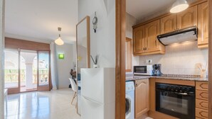 A kitchen with wooden cabinets, a built-in oven, a microwave, and a washing machine. - Magnificent Casa Azahara (Mont-roig del Camp)