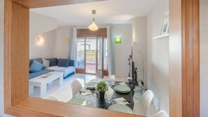 A dining area with a table set for four, a sofa, and a view of the outdoor balcony. - Magnificent Casa Azahara (Mont-roig del Camp)
