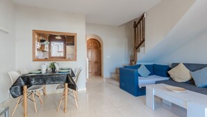 A modern living room with a dining area, a staircase, and a view of the outside. - Magnificent Casa Azahara (Mont-roig del Camp)