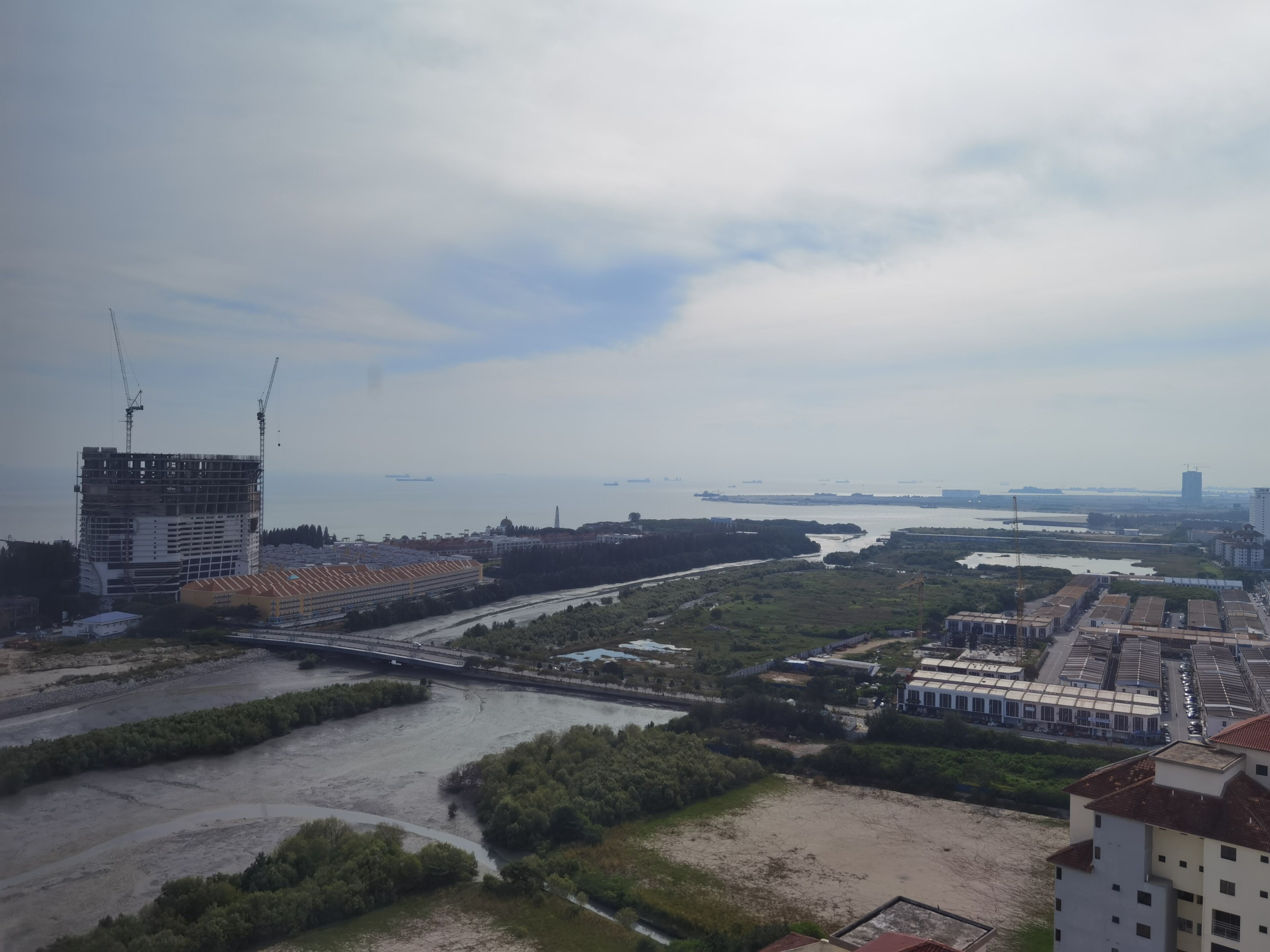 Une rivière avec un pont, un chantier de construction et des bâtiments en arrière-plan.