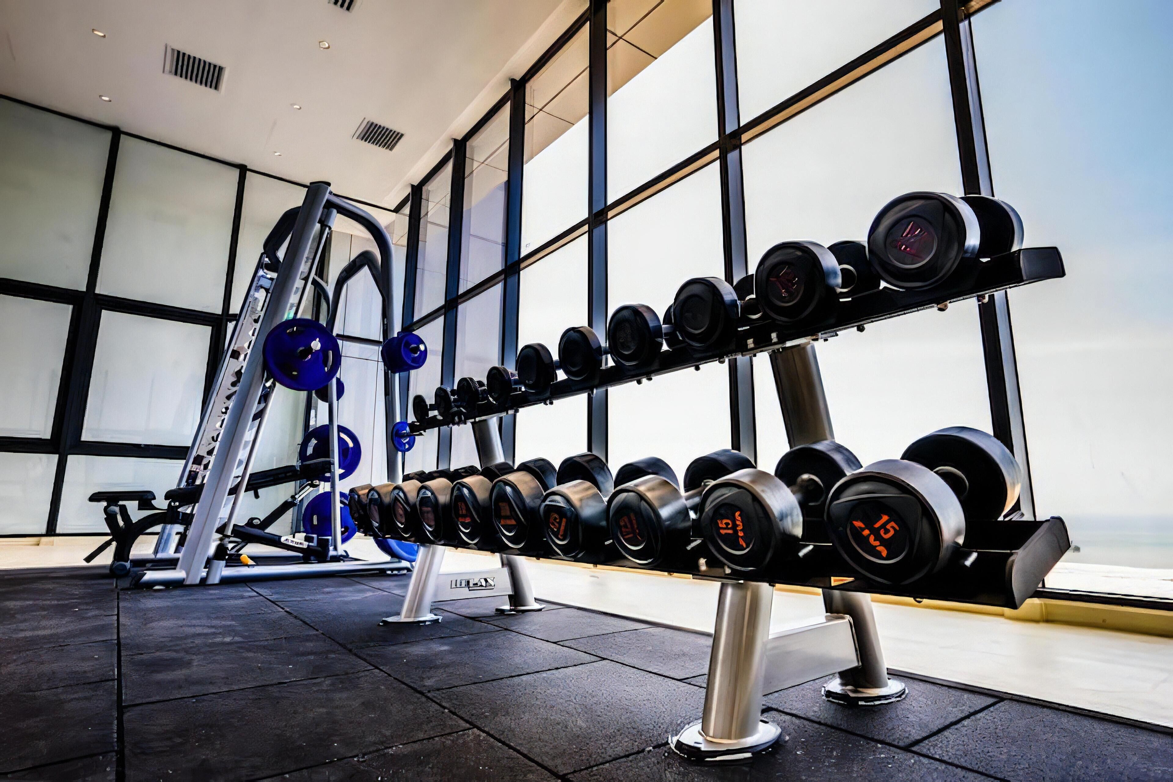 Une salle de sport équipée de matériel de musculation, notamment des haltères et un support à squats.