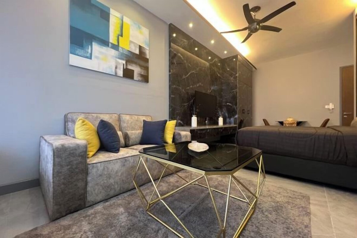 A modern living room with a grey sofa, a black coffee table with gold legs, and a ceiling fan.