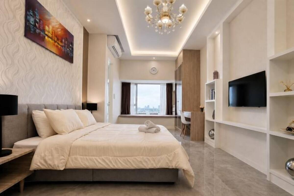 Habitación de hotel moderna con una cama grande, televisión, escritorio y vistas a la ciudad.