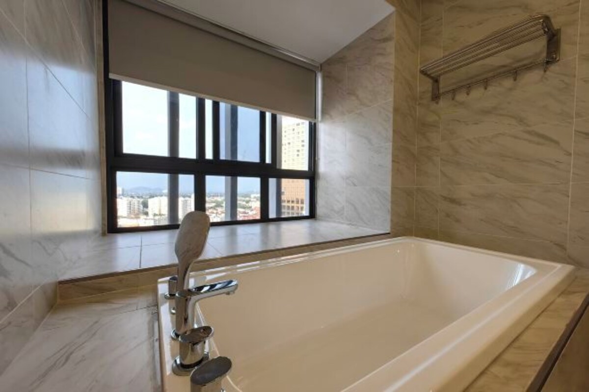 A modern bathroom with a large bathtub, a window with blinds, and a marble floor.