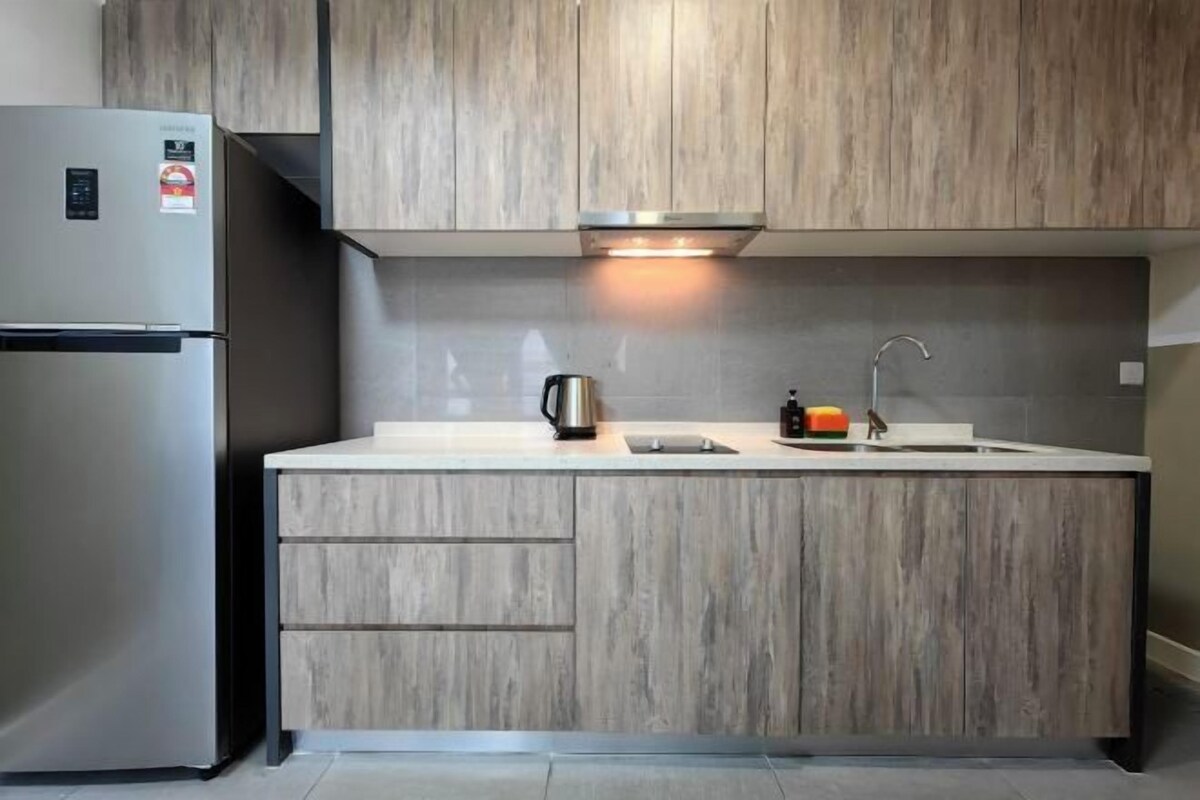 A modern kitchen with wooden cabinetry, a stainless steel refrigerator, a built-in oven, a kettle, and a sink.