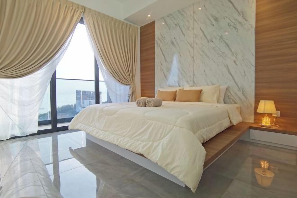 A modern bedroom with a large bed, a marble wall, and a view of the city.