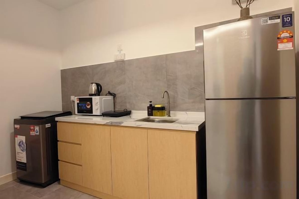 Una cucina compatta con frigorifero in acciaio inossidabile, forno a microonde e lavello.
