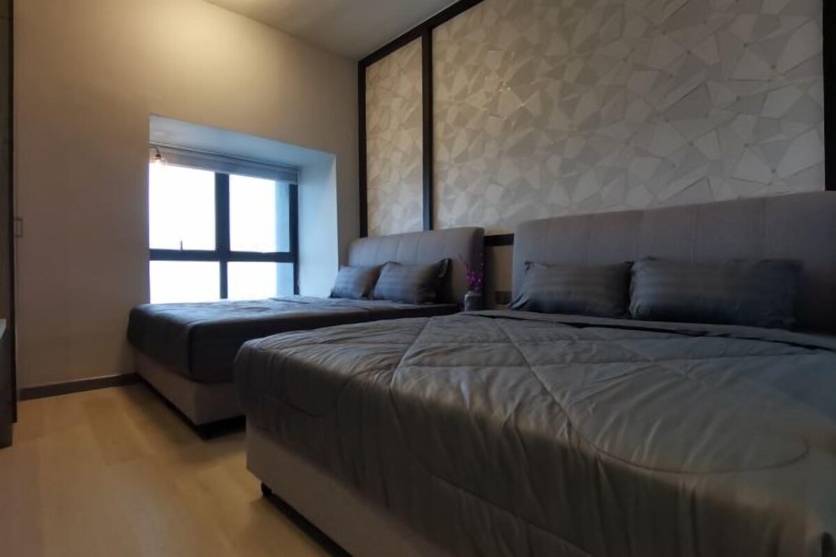 A hotel room with two beds, a window, and a textured wall.