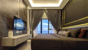 A modern bedroom with a large bed, a TV mounted on the wall, and a view of the sea through the window. - Attic Home Melaka Imperio Residence (Malacca City)