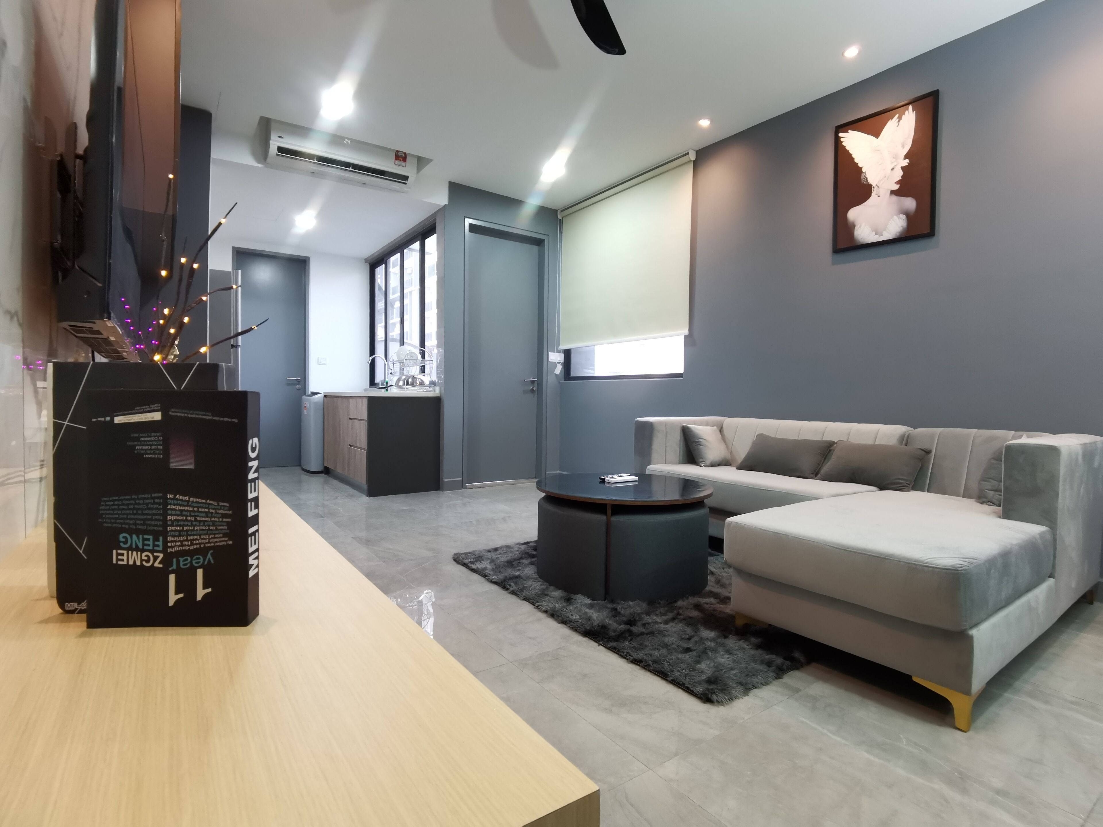 A modern living room with a grey sofa, a coffee table, and a dining area with a wooden table and chairs.