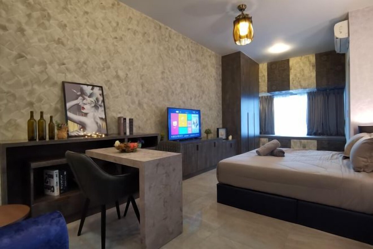 A modern hotel room with a bed, a desk, a television, and a large window with curtains.