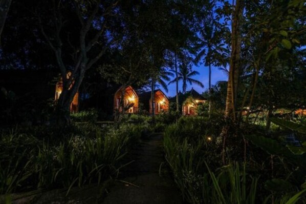 A pathway leading to a series of treehouse-style accommodations surrounded by dense tropical vegetation. - Bila Penida Resort & Farm (Penida Island)