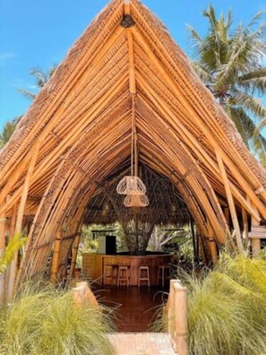 A thatched-roof structure with a central hanging light fixture, surrounded by lush greenery and palm trees. - Bila Penida Resort & Farm (Penida Island)