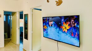 A hallway with a television displaying Buddha Flute Music, a Buddha statue, and three wooden crescent shapes on the wall.