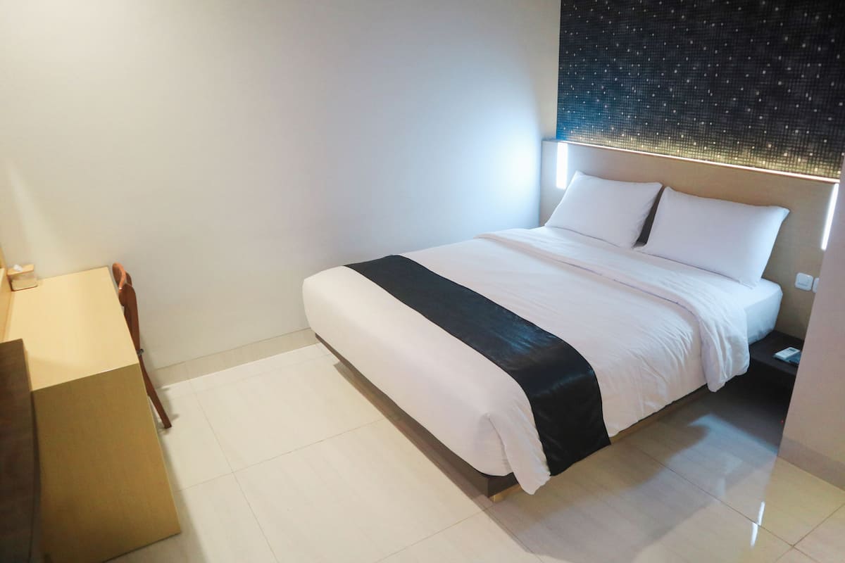 Ein modernes Hotelzimmer mit einem großen Bett, einem Nachttisch und einer Wandleuchte.