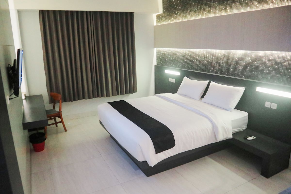 Ein modernes Hotelzimmer mit einem großen Bett, einem Schreibtisch und einem Stuhl.