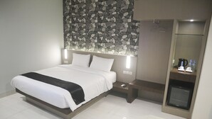 A modern hotel room with a large bed, a built-in heater, a small table with a phone, and a coffee maker. - LEX HOTEL BANJARMASIN BY EXCELSIOR (Banjarmasin)