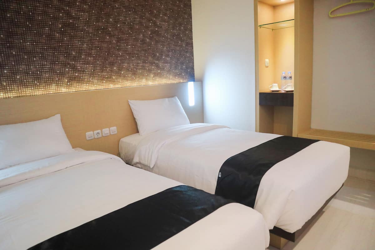 Ein Hotelzimmer mit zwei Betten, einem Spiegel und einem kleinen Badebereich.