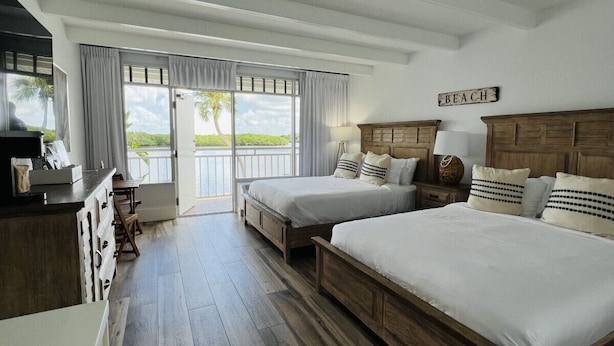 Un dormitorio con dos camas, cabecero de madera, un escritorio y vistas al exterior.
