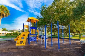 Explore the playground's climbing area and slide amidst lush greenery.