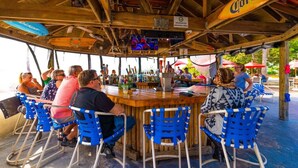Una zona de bar con vigas de madera, sillas azules y un letrero de Corona.