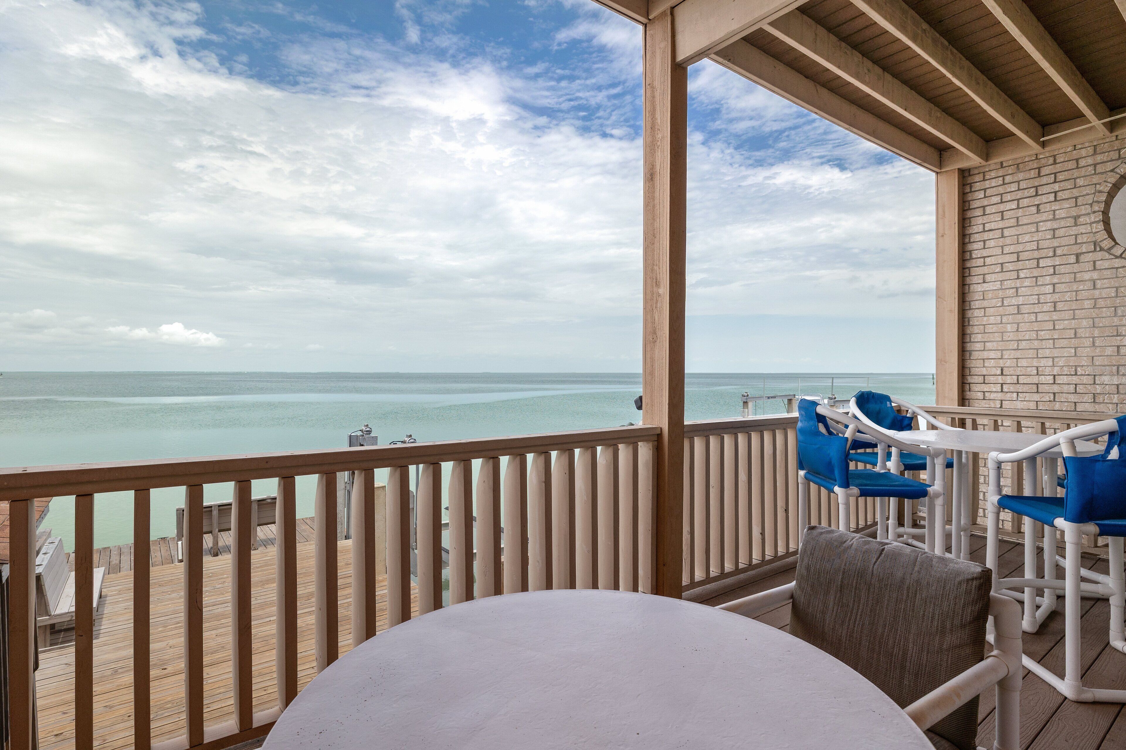 A covered outdoor area with a table and chairs, overlooking a body of water.