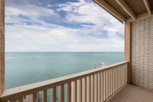 A balcony with a view of the sea and a brick wall.