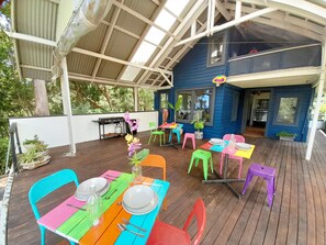 A covered outdoor area with colorful tables and chairs, a grill, and potted plants. - Sky Island Studios (Clagiraba)