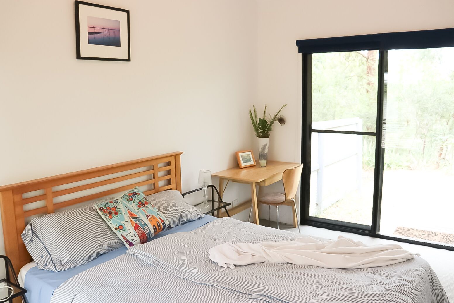 A bedroom with a bed, a desk, and a window.