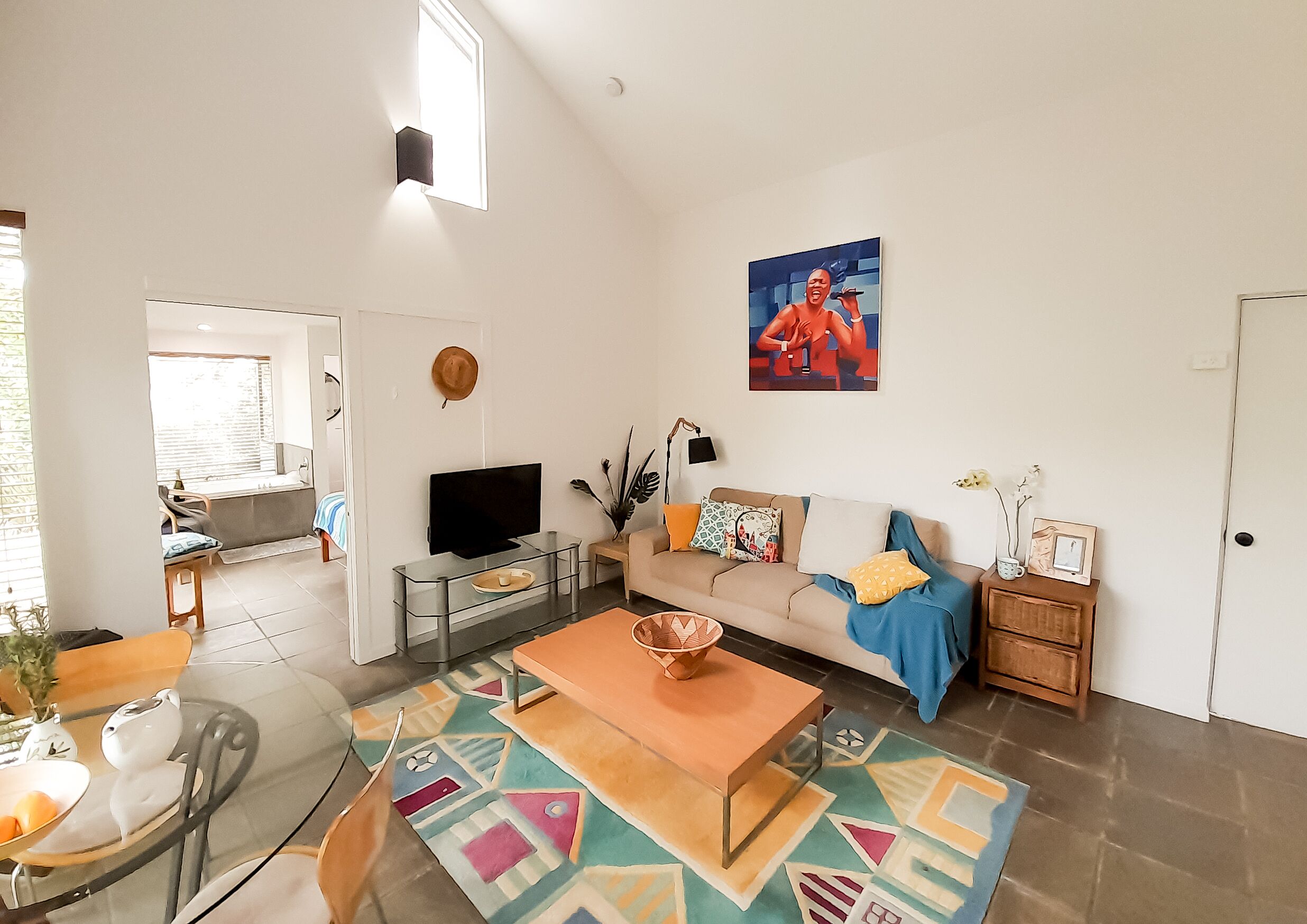 A spacious living room with a TV, sofa, coffee table, and a colorful rug.