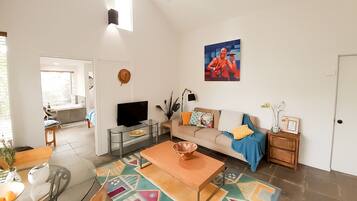 A spacious living room with a TV, sofa, coffee table, and a colorful rug.