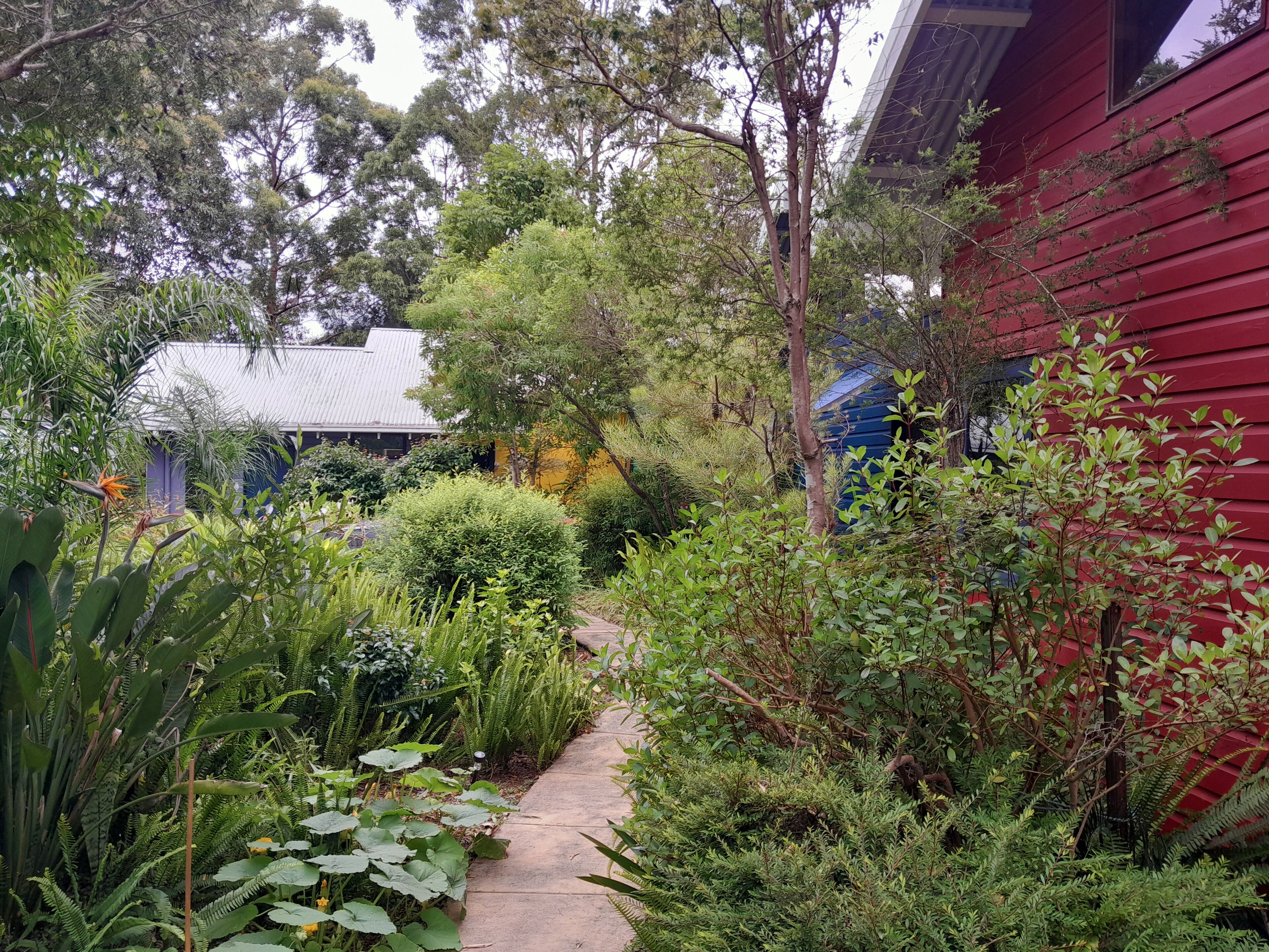 A garden pathway leading to a house with a red exterior.