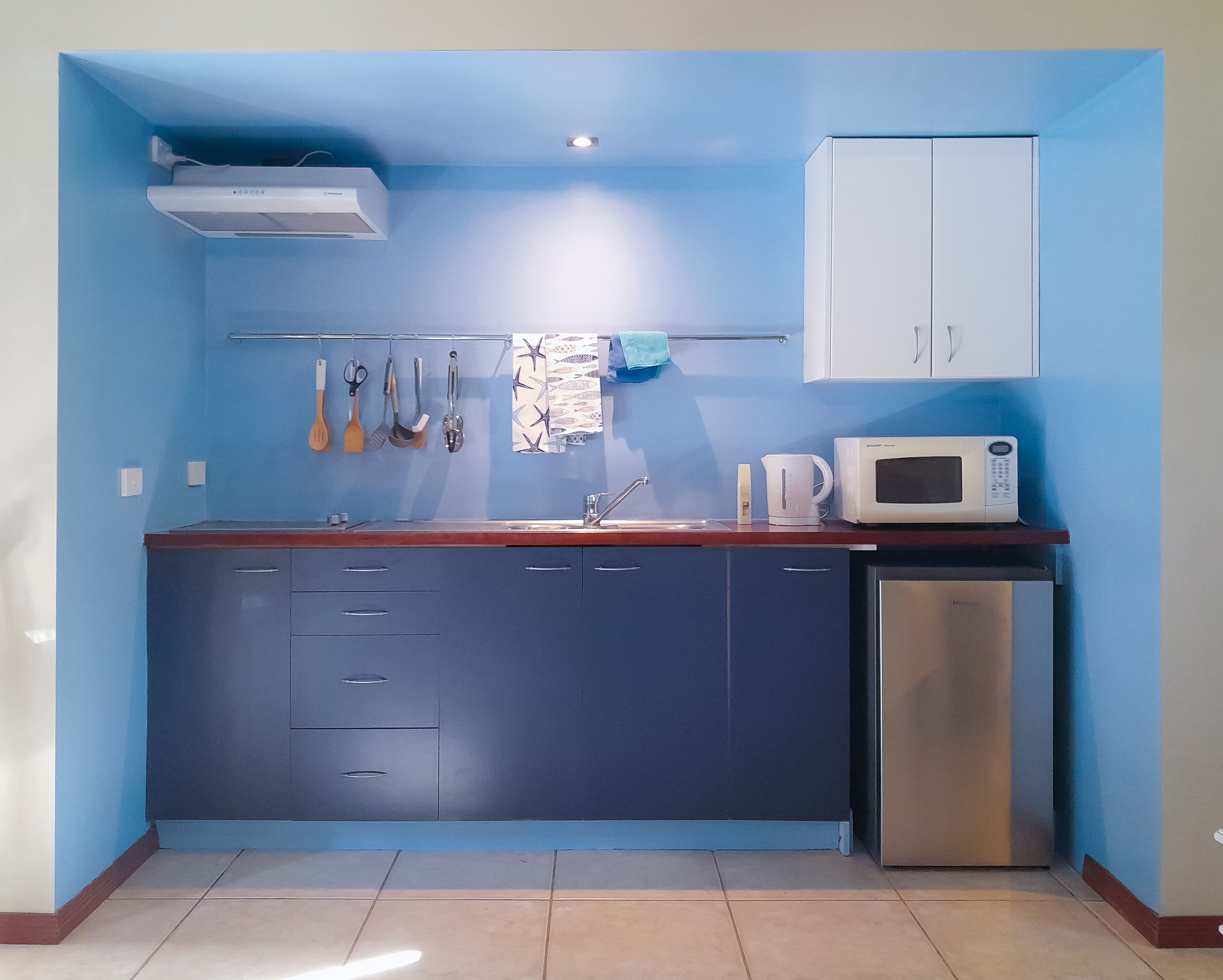 A compact kitchen with a microwave, sink, and cabinets.