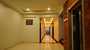 A hotel hallway with a polished floor, recessed lighting, and a view of the city in the distance.