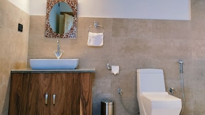 A bathroom with a wooden ceiling, a sink with a mirror, a toilet, and a shower. - The Merak (Leh)
