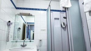 A bathroom with a white sink, a mirror, a handheld hair dryer, and a glass shower enclosure. - Logis Hotel de la Tour (Libourne)