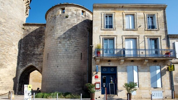 A historic stone tower adjacent to a modern building with a balcony. - Logis Hotel de la Tour (Libourne)