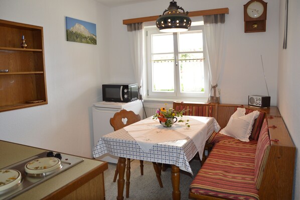 A cozy room with a dining table, a microwave, a sofa, and a clock on the wall. - Vacation in the Allgäu, vacation home Dorn (Altusried)