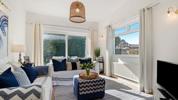 En moderne stue med en sofa, skammel og et fjernsyn.