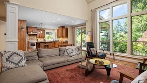 A spacious living area with a large window, a kitchen with wooden cabinets, and a cozy seating arrangement. - Impeccable Décor and Furnishing, Splendid Neighborhood, Pet Friendly, Fenced Backyard, Next to Park (Portland)