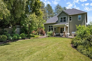 A two-story house with a covered patio, a lawn, and a wooden fence. - Impeccable Décor and Furnishing, Splendid Neighborhood, Pet Friendly, Fenced Backyard, Next to Park (Portland)